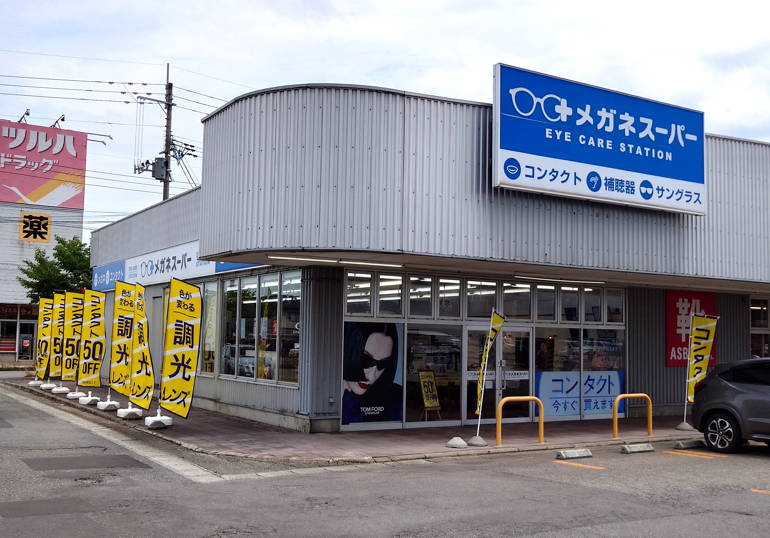 メガネスーパー鶴岡南SC店の店外斜めから、調光レンズののぼりとTOMFORDのカッティングシートが見える