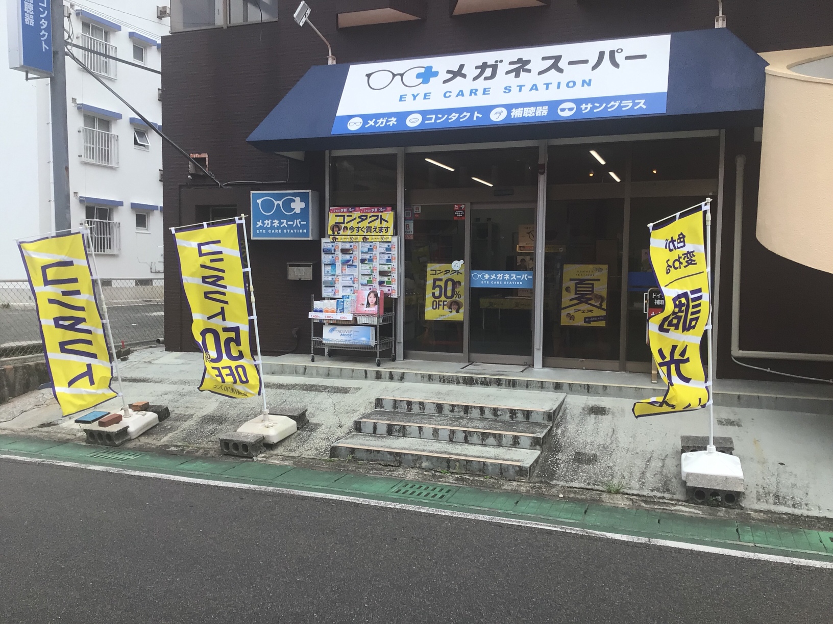 「メガネスーパー徳之島店の外観、コンタクト商品が⾒える⼊⼝