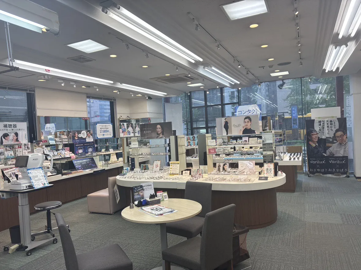 メガネスーパー鹿児島中央駅前店の店内、白と木目調の什器を使用した店内売場